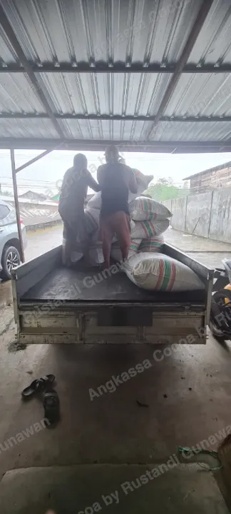 Dua orang menata karung di bak mobil pikap.